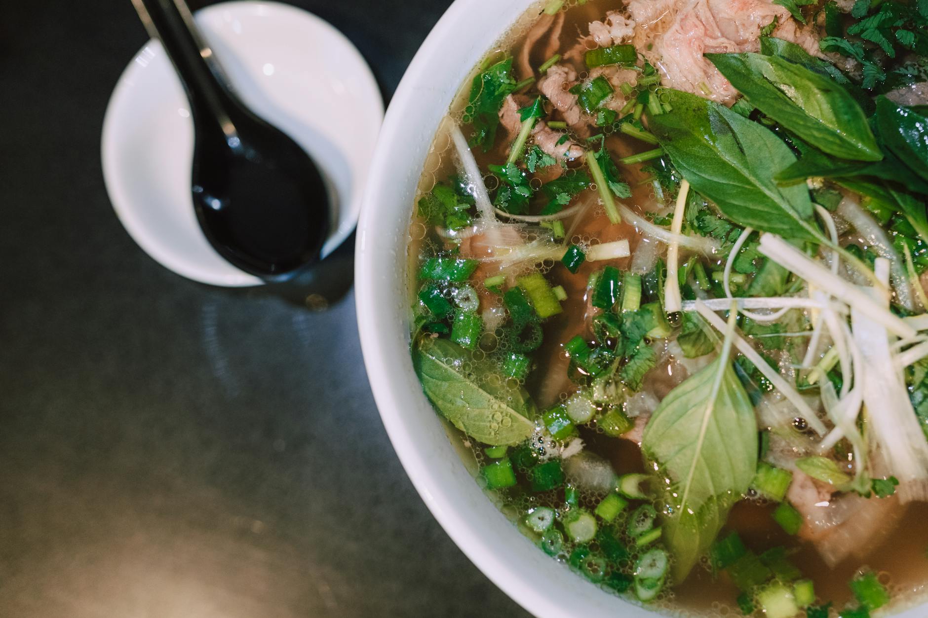 Bowl of pho with fresh herbs, lime and chili in a Hanoi restaurant